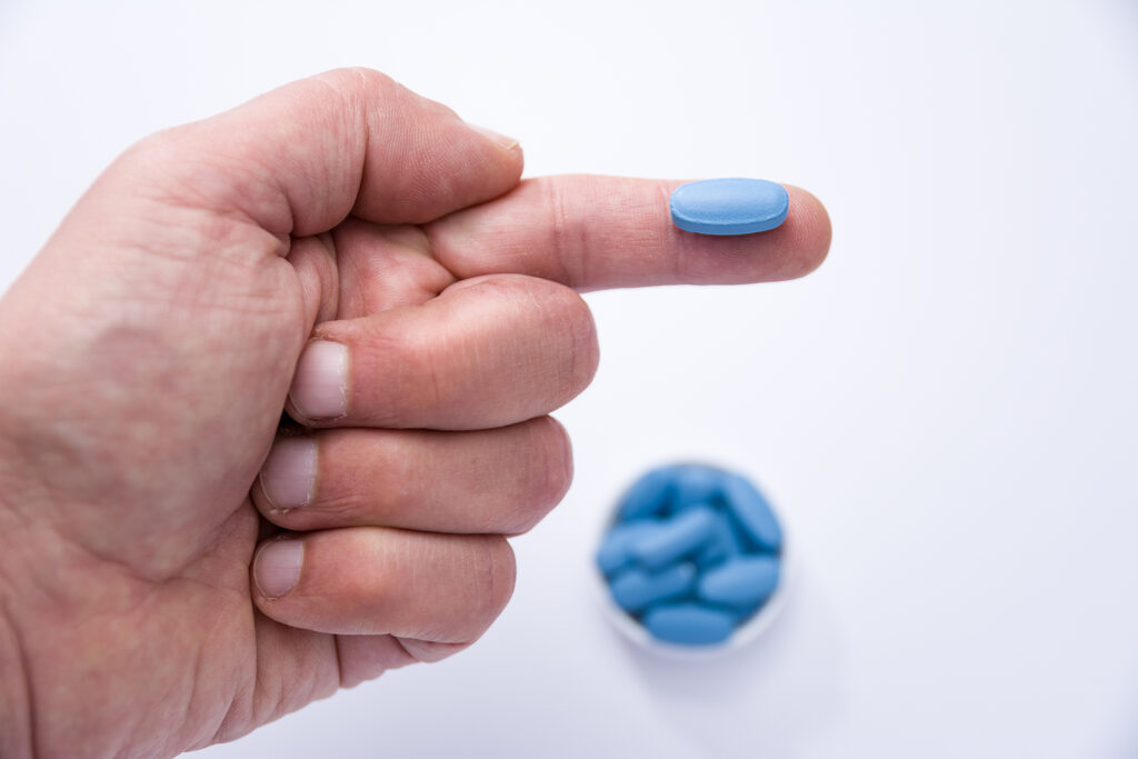 cheap sildenafil - Male hand showing a blue pill on a finger